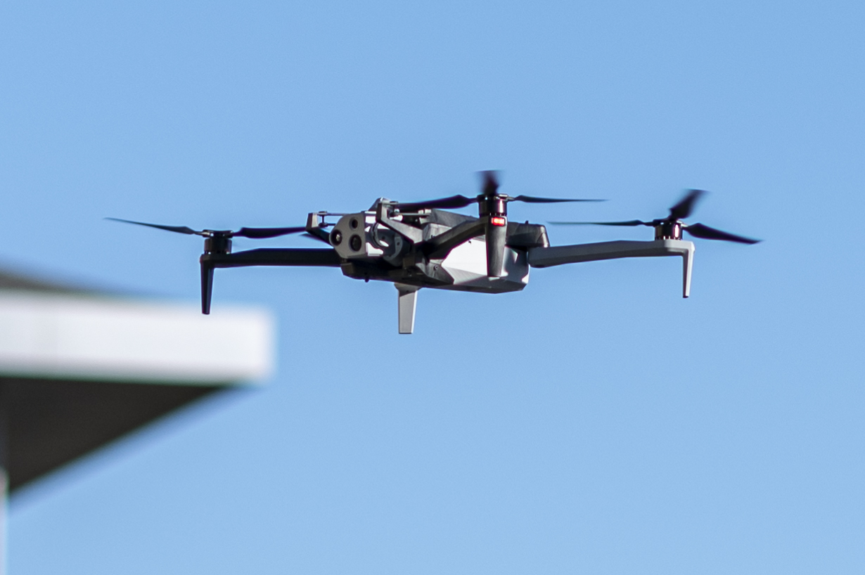 Skydio X10 quadcopter in flight, multi-sensor gimbal slung under the nose